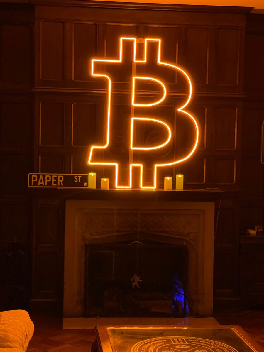 Símbolo de Bitcoin en neón naranja sobre la chimenea de La Crypta